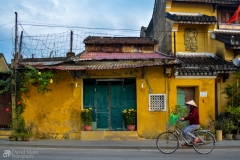 Vietnamese Women on Bike in Front of Yellow Building